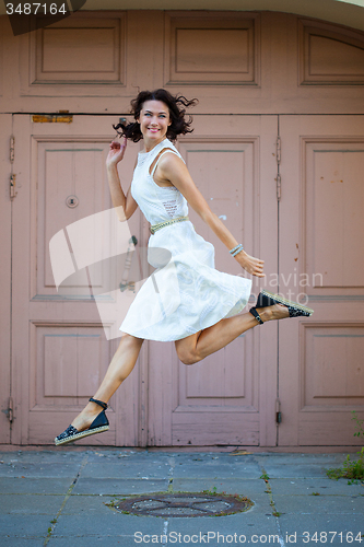 Image of beautiful brunette  jumped in a white dress