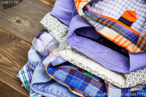 Image of stack of colored cotton shirts on a wooden shelf