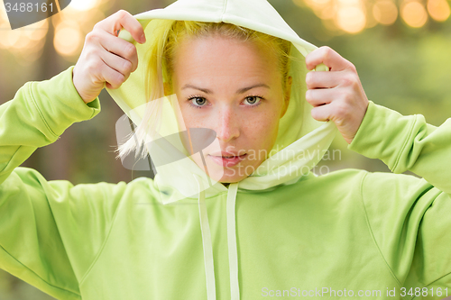 Image of Confident sporty woman wearing fashionable green hoodie. 