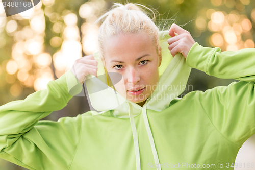 Image of Confident sporty woman wearing fashionable green hoodie. 