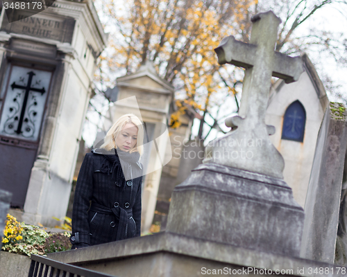 Image of Solitary woman visiting relatives grave.