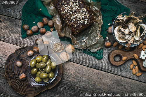 Image of healthy olives, nuts mushrooms  and bread on wood