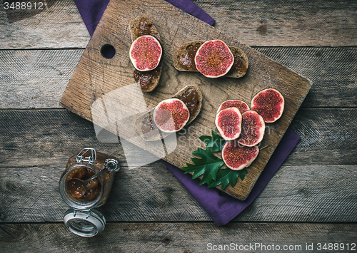 Image of figs, nuts and bread with jam on wooden choppingboard