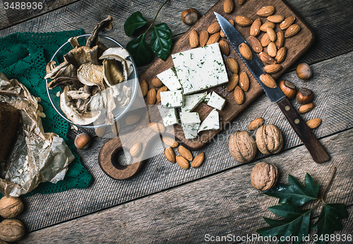 Image of Sheep cheese, nuts mushrooms on wooden table