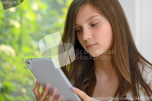 Image of Serious young girl reading  on a tablet computer