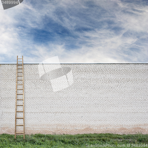 Image of Blue sky behind the huge wall with a wooden ladder