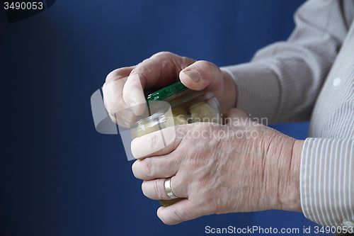 Image of Senior man tries to open jar.