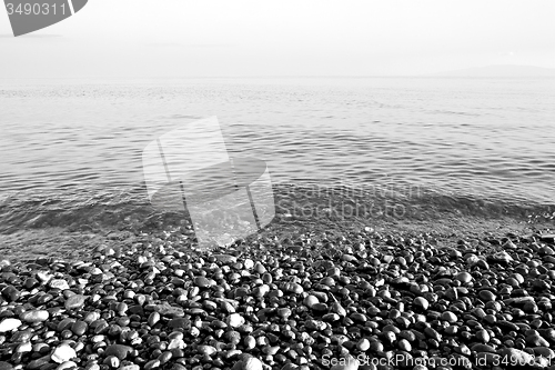 Image of stone in the coastline sunrise and light ocean white sky