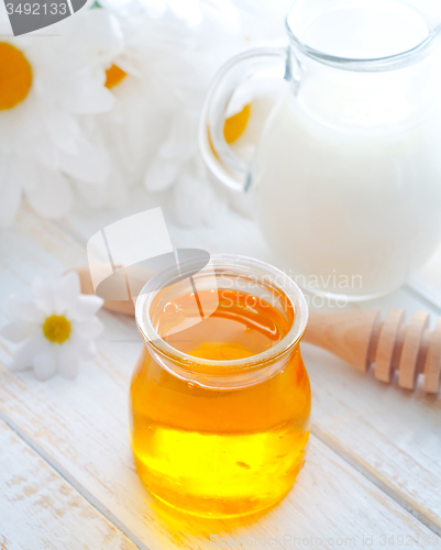 Image of fresh honey in the glass bank and milk in jug