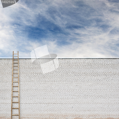 Image of Blue sky behind the huge wall with a wooden ladder