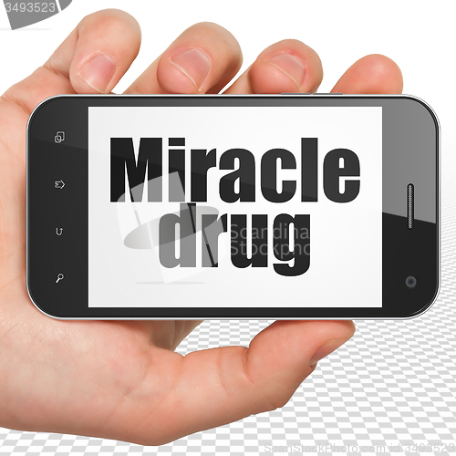 Image of Medicine concept: Hand Holding Smartphone with Miracle Drug on display