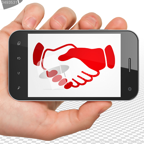 Image of Political concept: Hand Holding Smartphone with Handshake on display