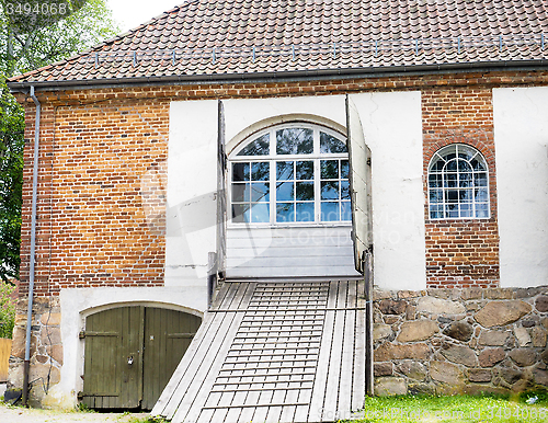 Image of Old red brick building with wooden bridge path towards blue wind