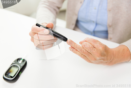 Image of senior woman with glucometer checking blood sugar