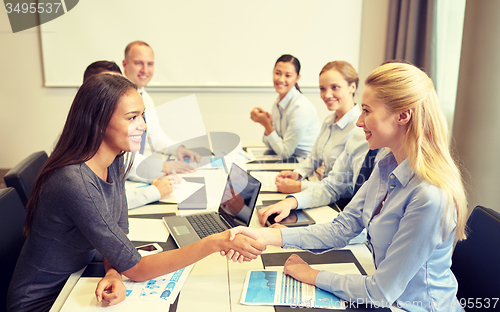 Image of smiling business people shaking hands in office