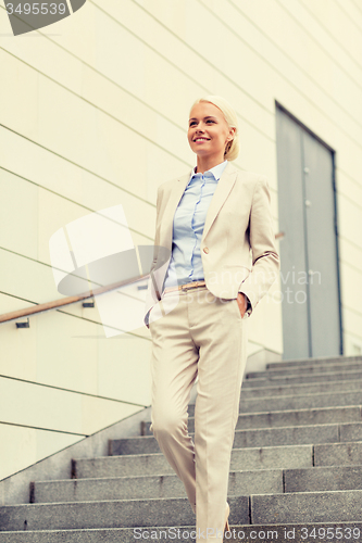Image of young smiling businesswoman walking down stairs