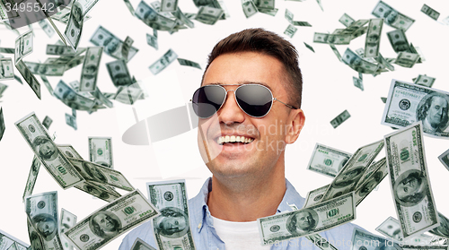 Image of happy man in sunglasses with falling dollar money