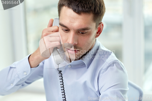 Image of face of businessman calling on phone in office