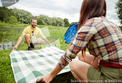 Image of happy couple laying picnic blanket at campsite