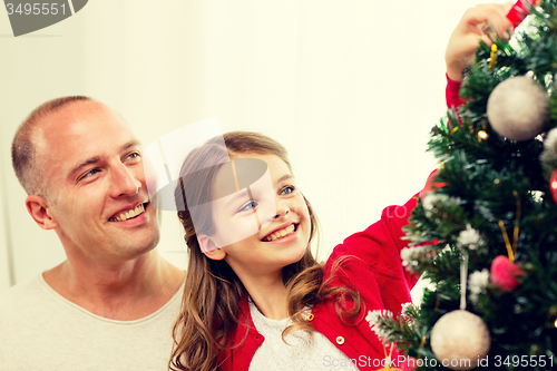 Image of smiling family decorating christmas tree at home