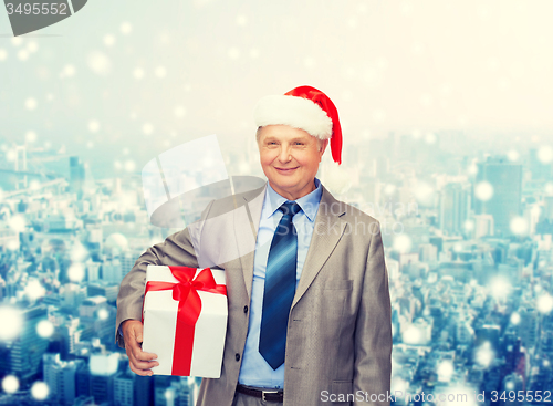Image of smiling man in suit and santa helper hat with gift