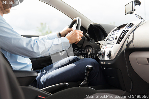Image of close up of young man in suit driving car