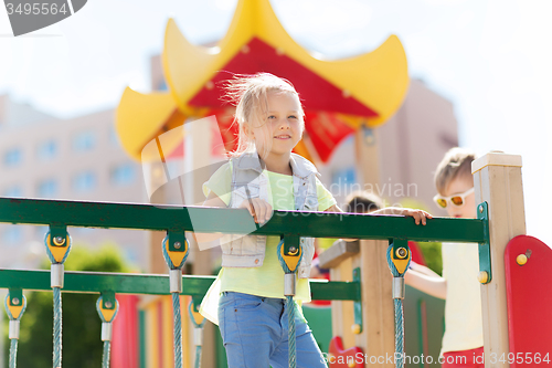 Image of happy little girl climbing on children playground