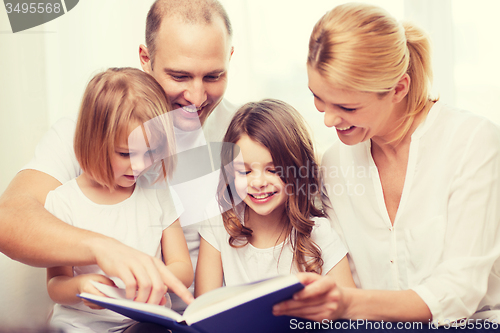 Image of smiling family and two little girls with book
