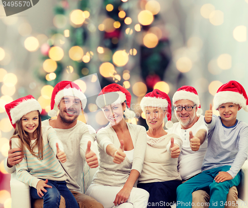 Image of happy family in santa hats showing thumbs up