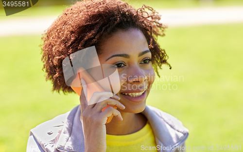 Image of happy african woman calling on smartphone outdoors