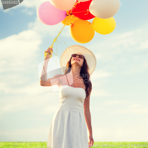 Image of smiling young woman in sunglasses with balloons