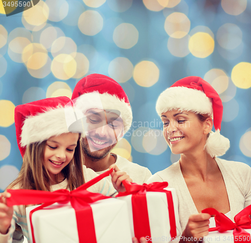 Image of happy family in santa helper hats with gift boxes