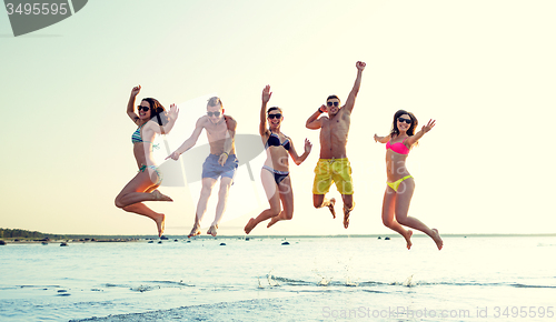 Image of smiling friends in sunglasses on summer beach