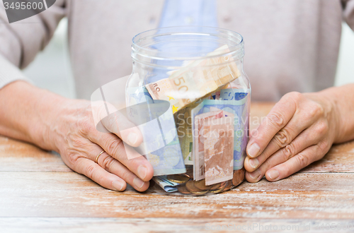 Image of close up of senior woman with money in glass jar