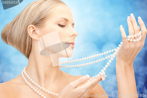 Image of beautiful woman with sea pearl necklace over blue