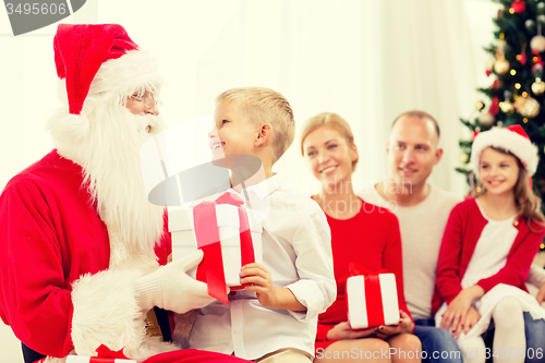 Image of smiling family with santa claus and gifts at home