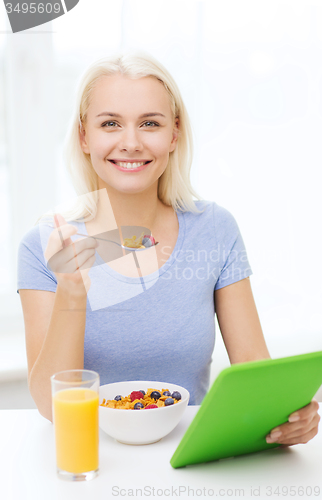 Image of smiling woman with tablet pc eating breakfast 