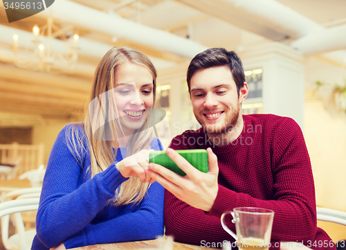Image of smiling couple with smartphone drinking tea