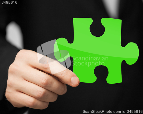 Image of close up of man holding green puzzle piece