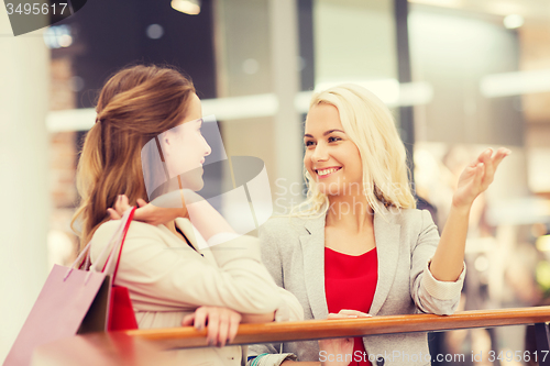 Image of happy young women with shopping bags in mall