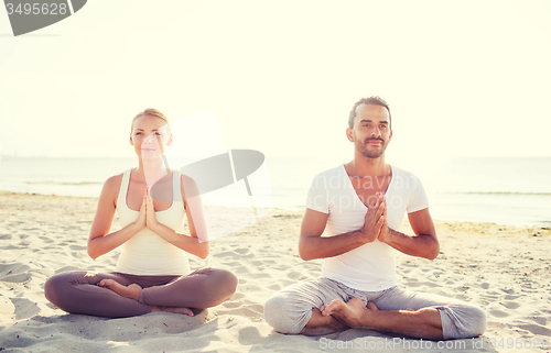 Image of smiling couple making yoga exercises outdoors