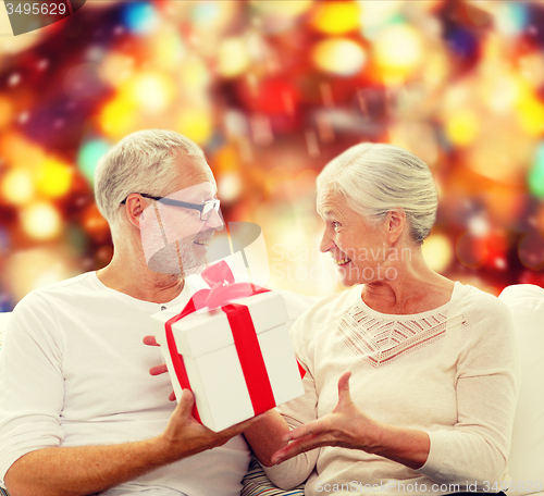 Image of happy senior couple with gift box at home