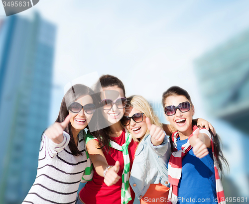 Image of happy teenage girls showing thumbs up at city