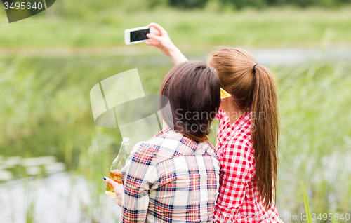 Image of happy women taking selfie by smartphone outdoors