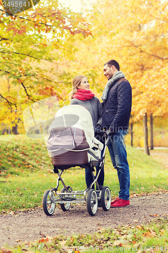 Image of smiling couple with baby pram in autumn park