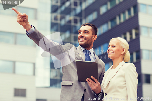 Image of smiling businessmen with tablet pc outdoors
