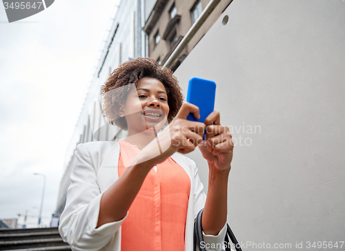 Image of happy african woman with smartphone in city