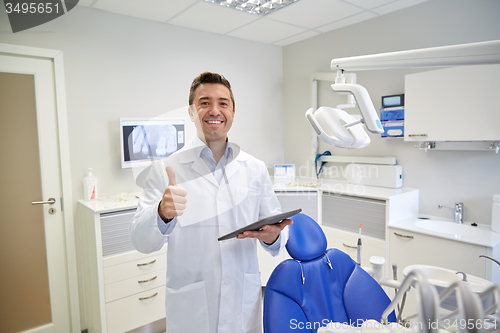 Image of happy dentist showing thumbs up with tablet pc