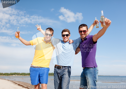 Image of happy friends with beer bottles on beach