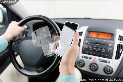 Image of close up of man hand with smartphone driving car